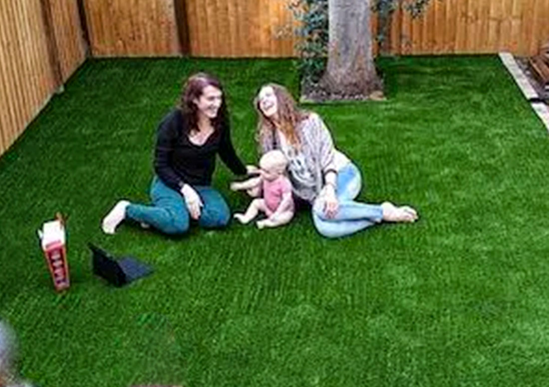 Mother enjoying artificial turf outdoors with baby