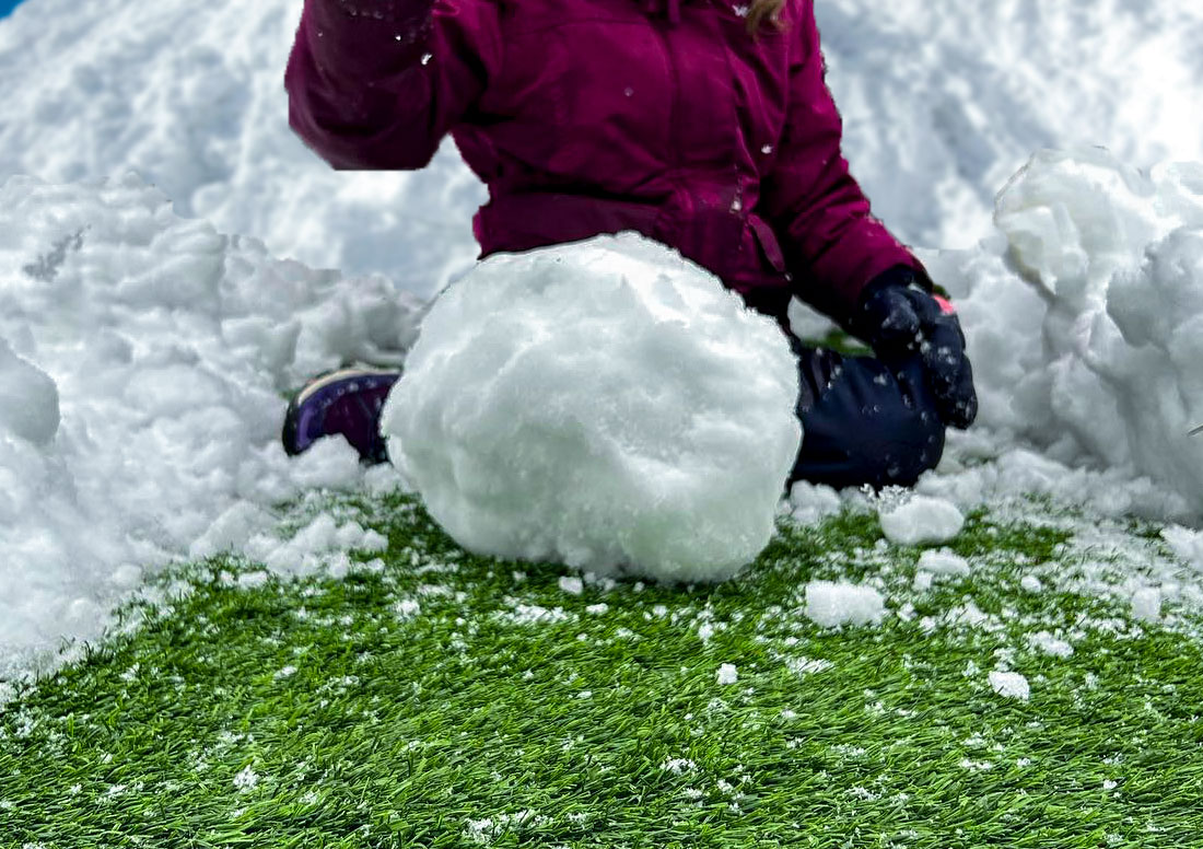 Building Snowman on artificial turf in the winter