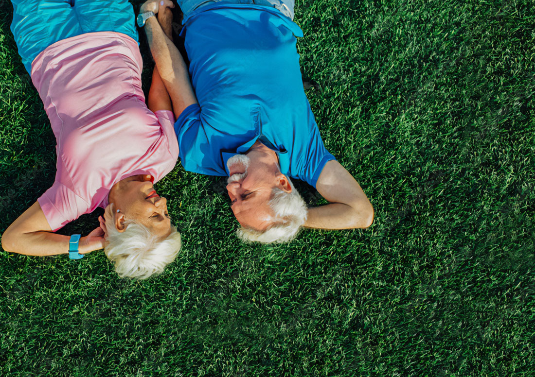 Senior couple laying on artificial turf